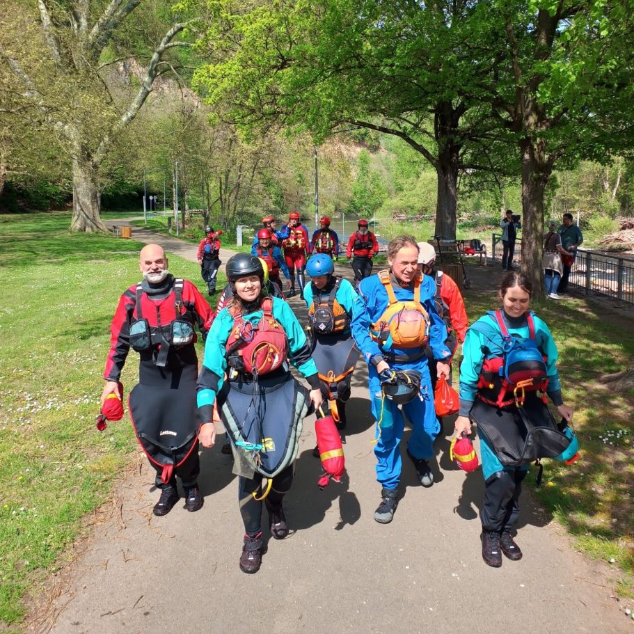 Wildwasser-Sicherheitskurs in Bad Kreuznach mit der DLRG Gruppe von Wassersportlern in Schutzkleidung geht einen Weg entlang.