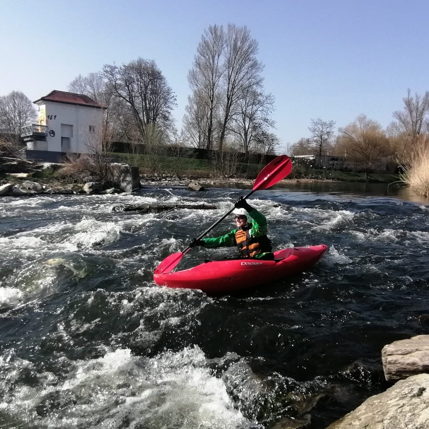 Ein Paddler in einem roten Kajak fährt über ein reißendes Gewässer.