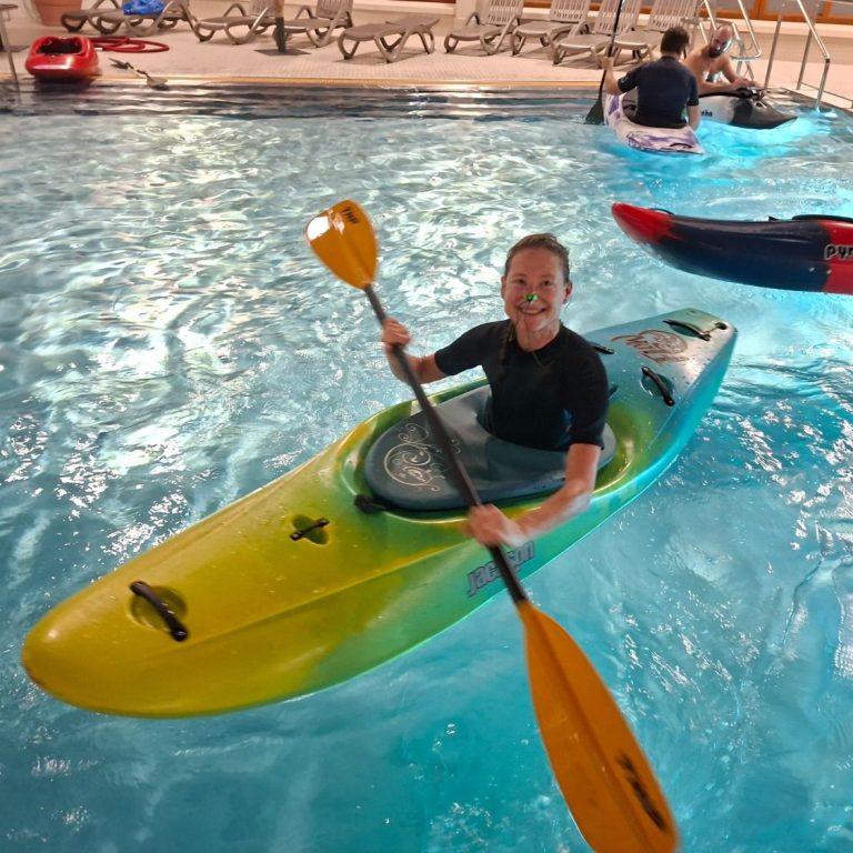 Eskimotraining im Höchster Hallenbad Frau im blauen Kajak paddelt im Wasser eines Schwimmbads.