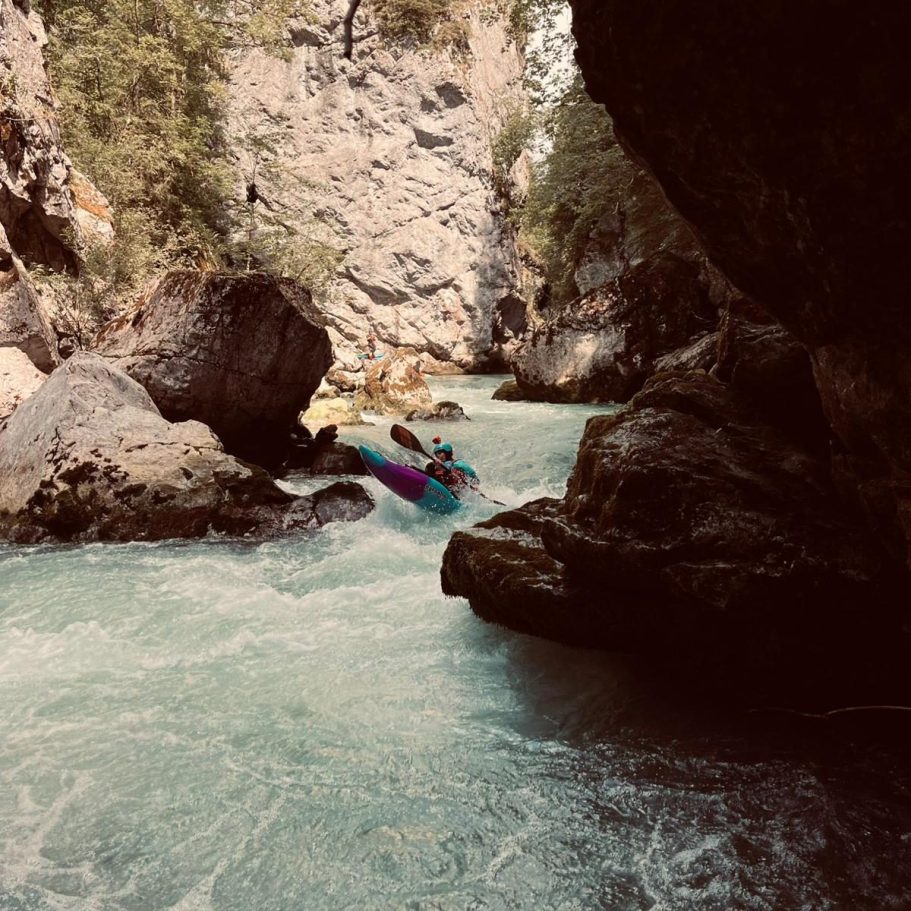 Paddeln auf der Saane – Kernstelle Saane-S Kajakfahrer paddelt durch einen engen, felsigen Fluss mit klarem, türkisfarbenem Wasser.