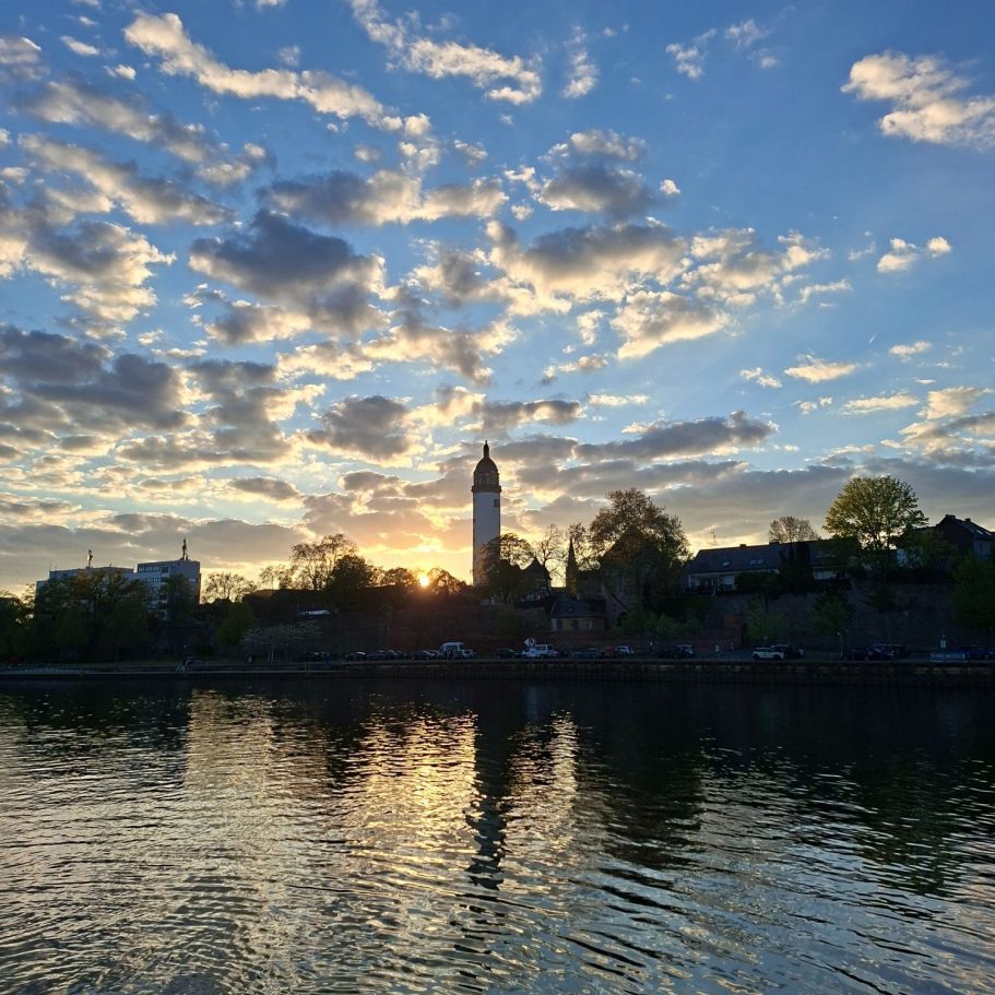 Höchster Schloss Sonnenuntergang über dem Fluss mit einer Silhouette vom Höchster Schloss und Wolken.