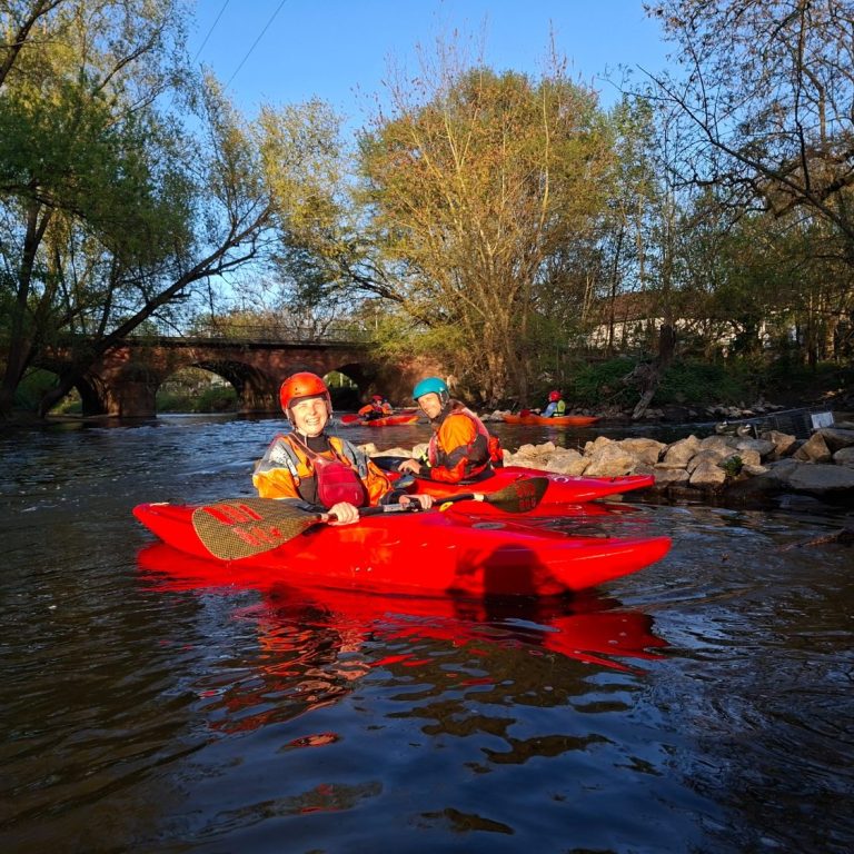 Kanutour auf der Nidda in Frankfurt am Main Mehre glückliche Kajakfahrer paddeln in Kajaks auf ruhigem Wasser, umgeben von grüner Natur.