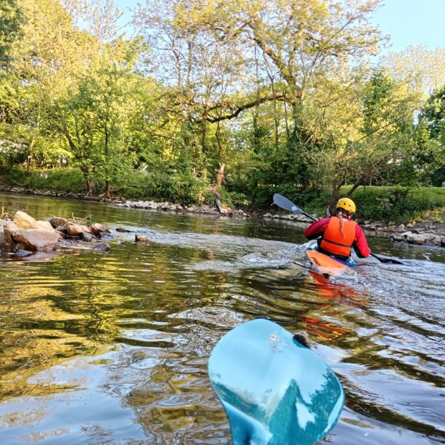 Jugendtraining auf der Nidda Kajakfahrer paddelt ruhig auf einem klaren Fluss, umgeben von Bäumen.