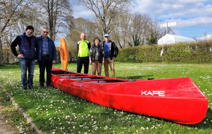 Neuer Kanadier vom Höchster Kanuclub Wiking Gruppierung von fünf Personen neben einem roten Kajak auf einer Wiese.