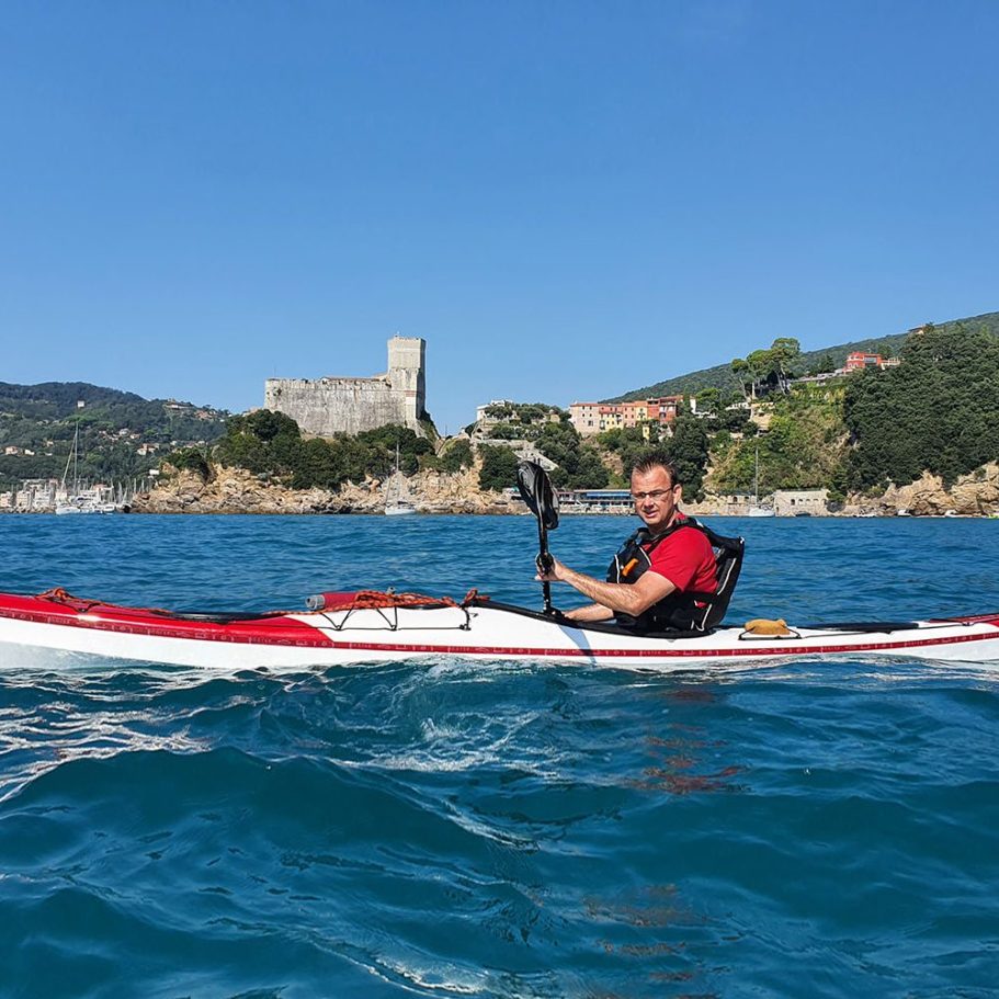 Mann im Kajak auf dem Wasser mit einer Burg im Hintergrund.